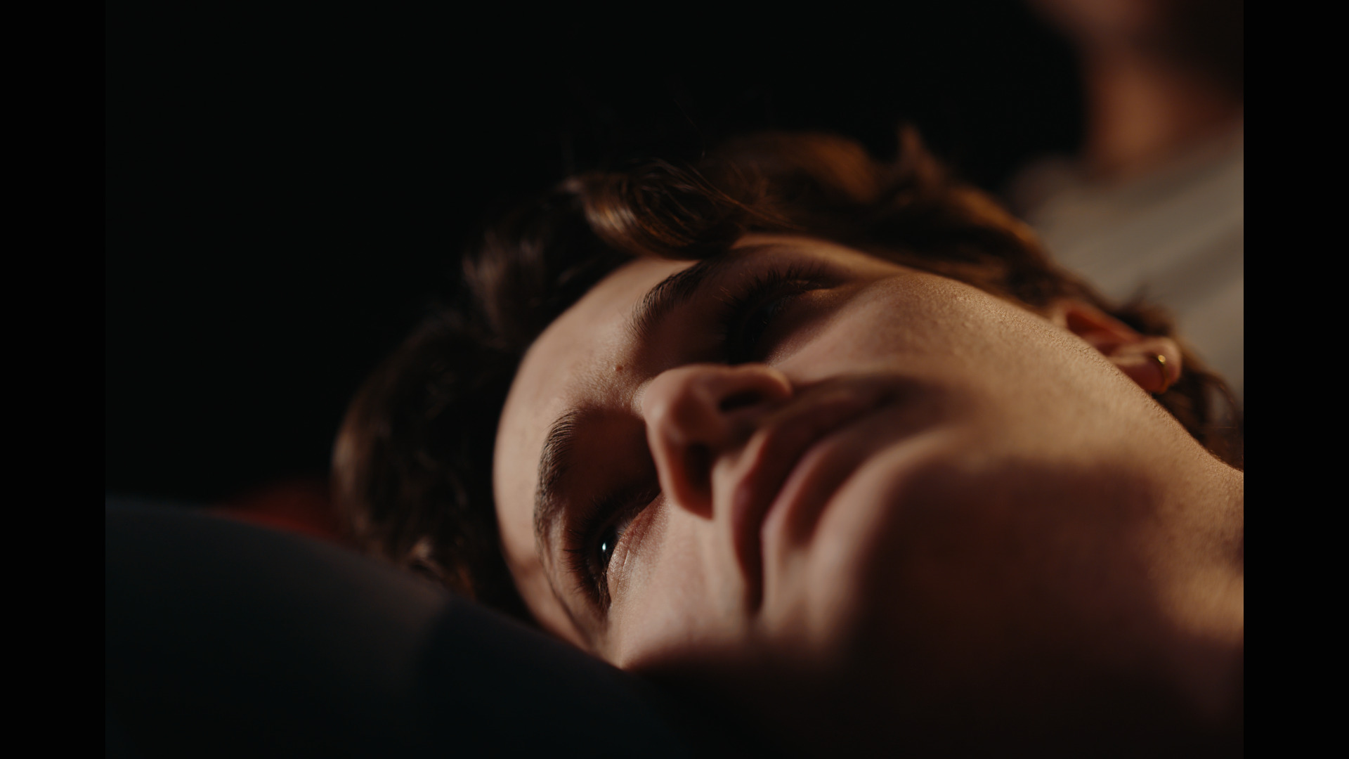 A close-up on Misha's face as he looks up into a light.