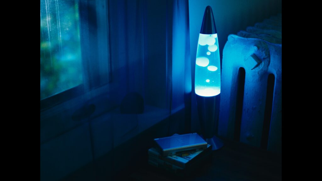 A lava lamp glows blue in the dark.