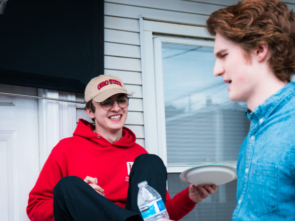 Sam (director) holds a paper plate while talking to Wyatt (script supervisor) at lunch.