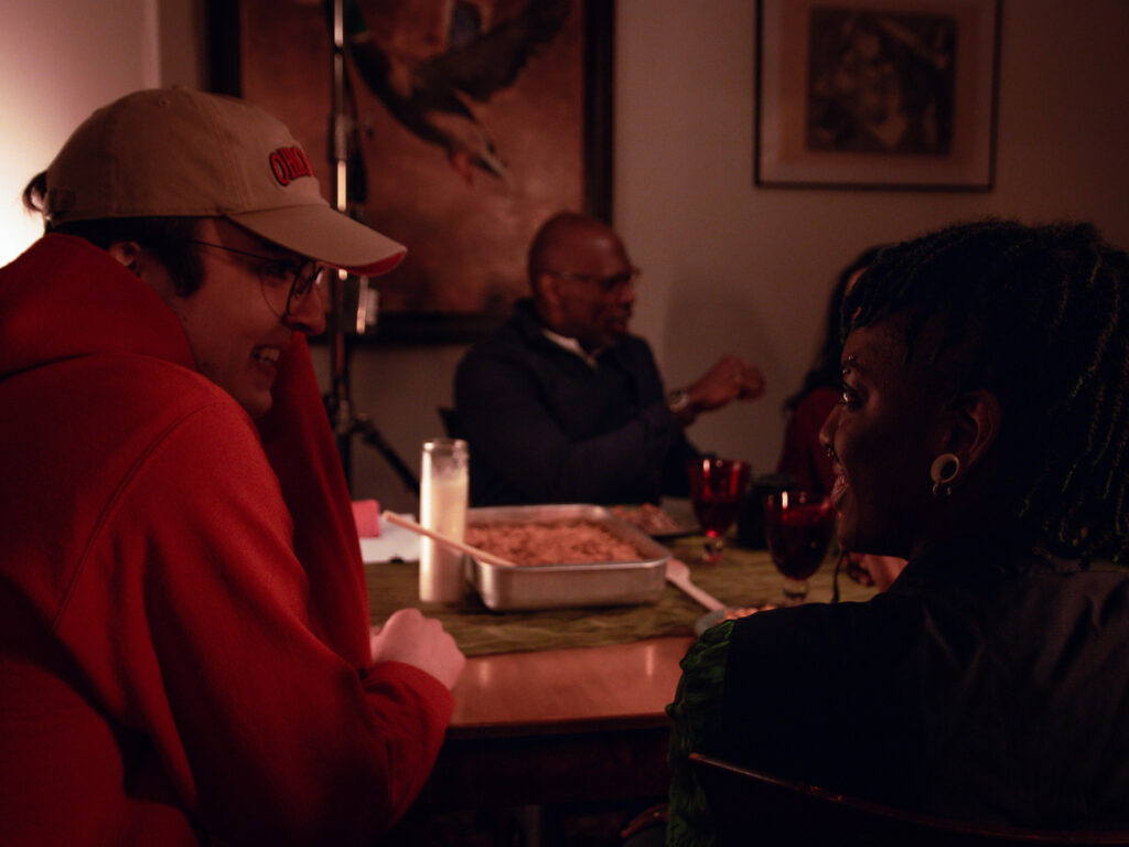 Sam (director) talks to Aiden (playing Constance) at the dinner table. David (playing John) can be seen in the background.