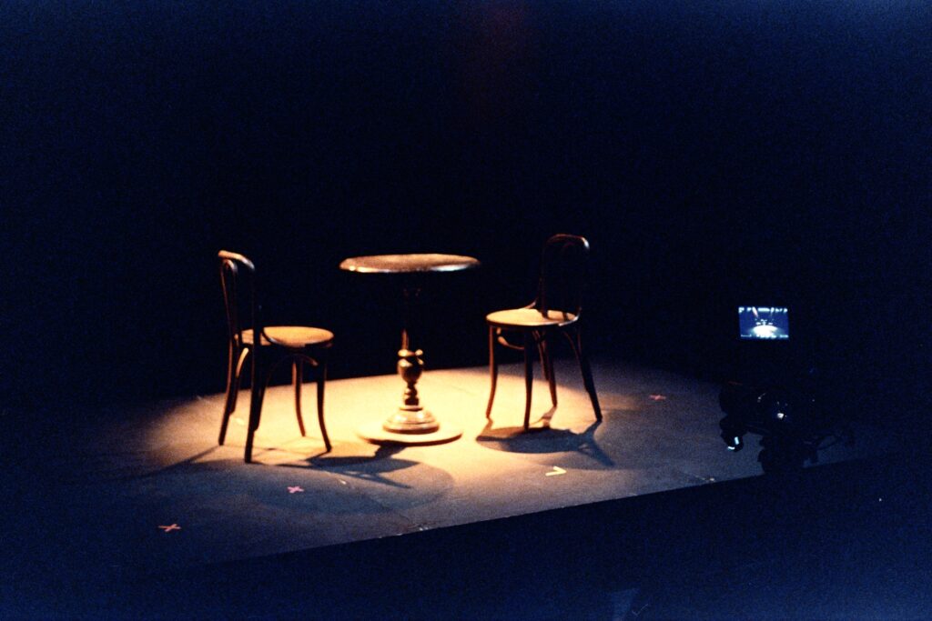 An empty table with empty chairs under a spotlight.